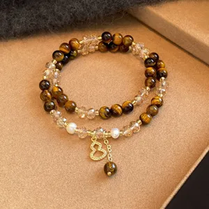 Dettaglio del bracciale con occhio di tigre, cristalli sfaccettati, perle e ciondolo a zucca dorato