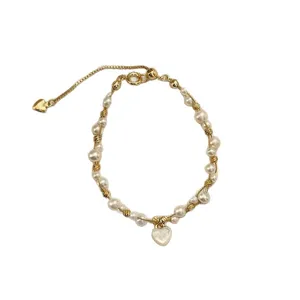 Bracciale dorato con perle bianche irregolari, ciondoli a cuore e catena regolabile