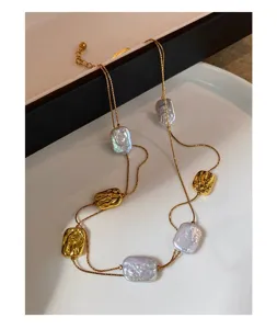Dettaglio della doppia catena dorata con perle barocche color lavanda e pendenti in rilievo