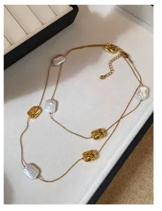 Dettaglio di una collana dorata a doppio filo con perle barocche e inserti metallici lavorati