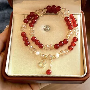 Bracciale a doppio filo con perline rosse, cristalli champagne e ciondolo dorato nel cofanetto
