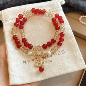 Primo piano di perline rosse, cristalli sfaccettati, accenti di perla e ciondolo dorato traforato