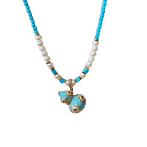 Collana blu di perline e perle bianche, con ciondolo a zucca smaltato turchese e dettagli dorati
