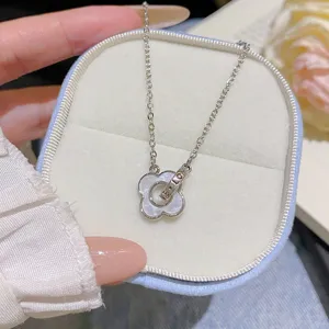Close-up of a silver chain and pearly four-petal pendant resting in a soft jewelry box