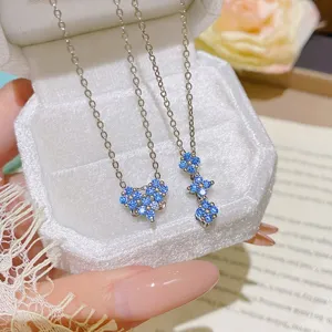 Close-up of two silver chains with blue crystal flower pendants on a white velvet jewelry box