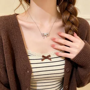 Close-up of a sparkling bow pendant on a fine silver chain, worn at the neckline