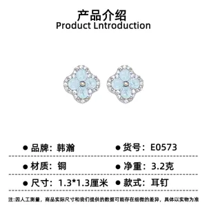 Pair of pale blue clover stud earrings with clear stone accents, displayed on a white product card