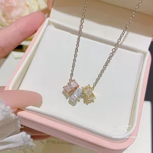 Close-up of a silver chain necklace with three square multicolor stones displayed in a jewelry box