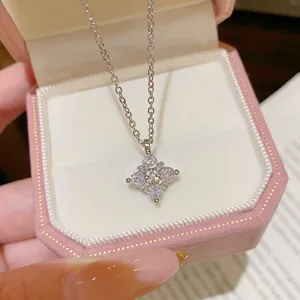 Close-up of a silver-tone chain and sparkling four-leaf flower pendant in a pink velvet box