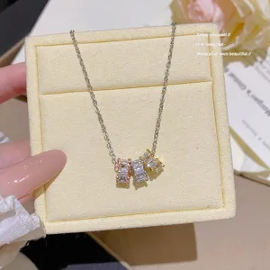 Close-up of three square zircon stones in mixed-tone settings on a silver chain against velvet