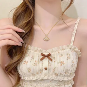 Gold-toned fan pendant with sparkling accents shown worn at the neck against a floral dress