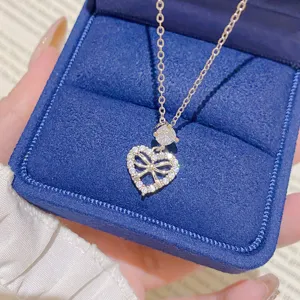 Close-up of a silver-tone heart-shaped bow pendant with clear stones in a blue velvet box