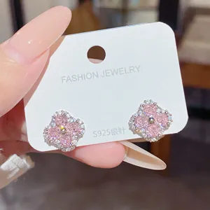 Close-up of pink four-petal stud earrings with clear stones on a white display card