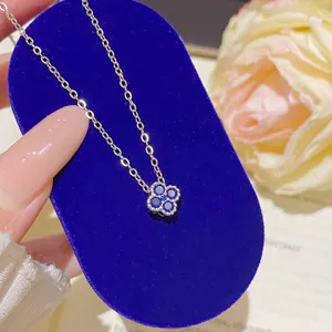 Close-up of a blue stone flower pendant with beaded edging on a silver-tone chain, displayed on velvet