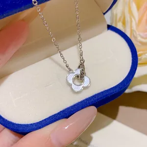 Close-up of a white shimmer four-leaf flower pendant with an open ring and LOVE lettering