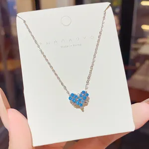 Close-up of a silver-tone chain with a clustered blue heart pendant displayed on a white card