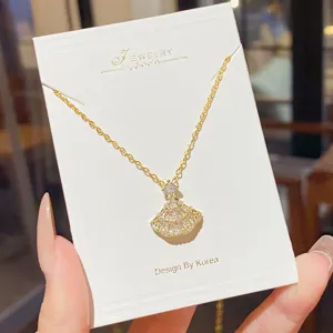 Close-up of a gold-tone chain and sparkling fan-shaped pendant displayed on a white jewelry card