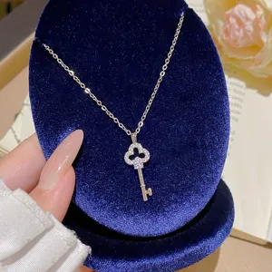 Close-up of a silver key pendant with a sparkling clover-shaped head on a navy velvet display