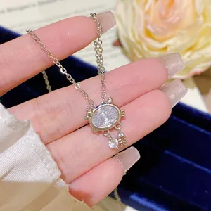 Close-up of an oval clear-stone pendant with paw details and a small dangling charm on a fine chain