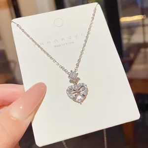 Silver-tone openwork heart pendant with clear stones, round accent, on a white display card