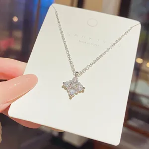 Close-up of a silver-tone chain and sparkling flower-shaped pendant displayed on a white jewelry card