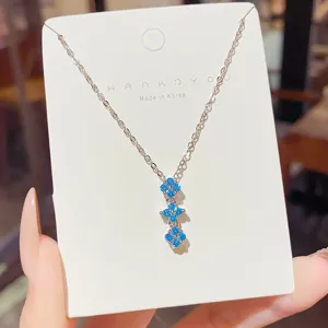 Silver-tone necklace with three blue floral gemstone clusters displayed on a white card
