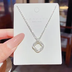Close-up of a silver open square pendant with layered woven edges and fine beaded texture on a display card