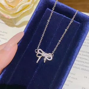 Close-up of a sparkling bow pendant necklace displayed on a deep blue velvet jewelry box