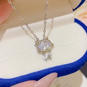 Close-up of an oval white zircon cat pendant with a tiny fishbone charm on a silver chain