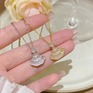 Close-up of silver and gold fan-shaped pendants with sparkling stones displayed across an open hand