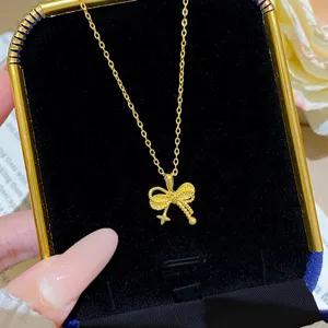 Close-up of a gold-tone bow pendant with a tiny star charm on a fine chain in a velvet box
