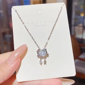 Close-up of a silver-tone cat-shaped pendant with an oval clear stone and two dangling charms