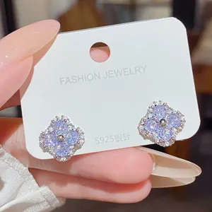 Close-up of lilac cubic zirconia four-leaf clover studs with silver-tone settings on a card
