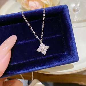 Close-up of a silver flower pendant with clear stones on a deep blue velvet jewelry box
