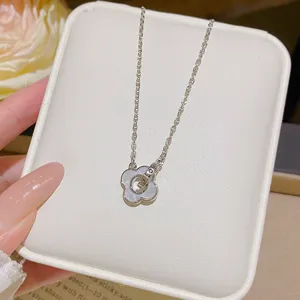 Close-up of a silver chain and white flower pendant with a small ring detail on a jewelry tray