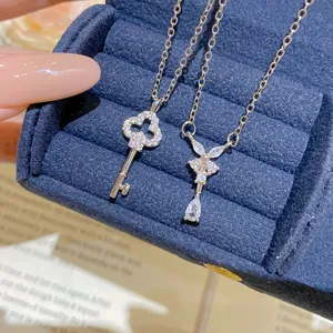 Close-up of two silver-tone key necklaces with zircon stones in a blue velvet jewelry box