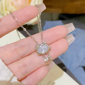 Close-up of a silver-tone cat pendant with an oval clear stone and dangling fishbone charm