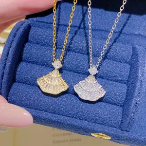 Close-up of gold and silver fan pendants with sparkling zircon rows in a blue velvet jewelry box