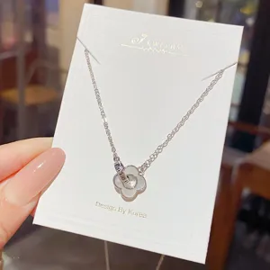Silver chain and translucent four-leaf flower pendant displayed on a white jewelry card