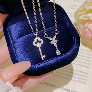 Two silver-tone necklaces with crystal key and floral teardrop pendants in a blue velvet box