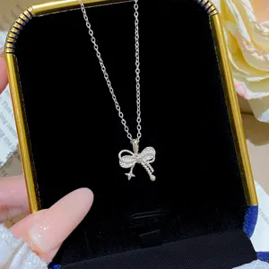Close-up of a sparkling silver bow pendant necklace displayed in a black velvet jewelry box