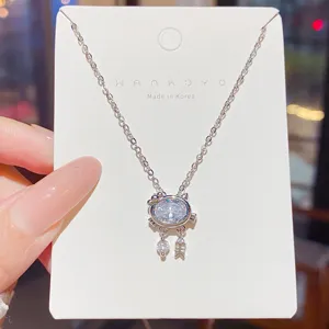 Close-up of a silver cat pendant with oval white zircon and dangling fish and round charms