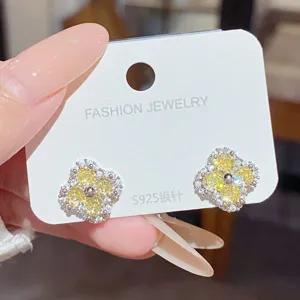 Close-up of yellow four-leaf flower studs with white stones on an S925 display card