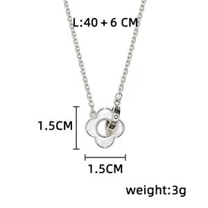 Close-up of a silver chain with a white four-leaf flower pendant and engraved ring, 1.5 cm wide