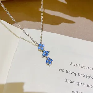 Close-up of three blue gemstone flower charms linked on a silver-tone chain, laid on a page