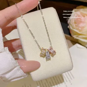 Close-up of three square-cut zircon pendants in gold, silver and rose gold on a silver chain
