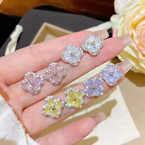 Close-up of clover studs with sparkling pink, white, purple and yellow stones on a hand