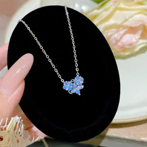 Close-up of a blue crystal flower pendant on a silver-tone chain against black velvet