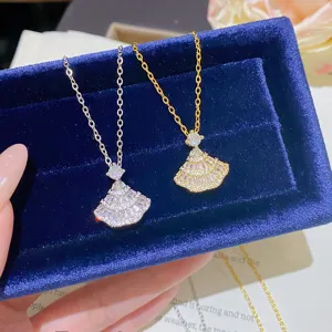 Close-up of silver and gold fan-shaped pendants with sparkling stones on a blue velvet display