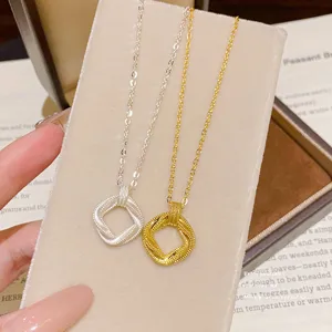 Close-up of silver and gold fine-chain necklaces with square twisted pendants on a display card